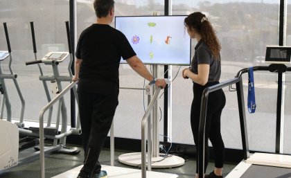 Man on exercise machine being watched by a woman